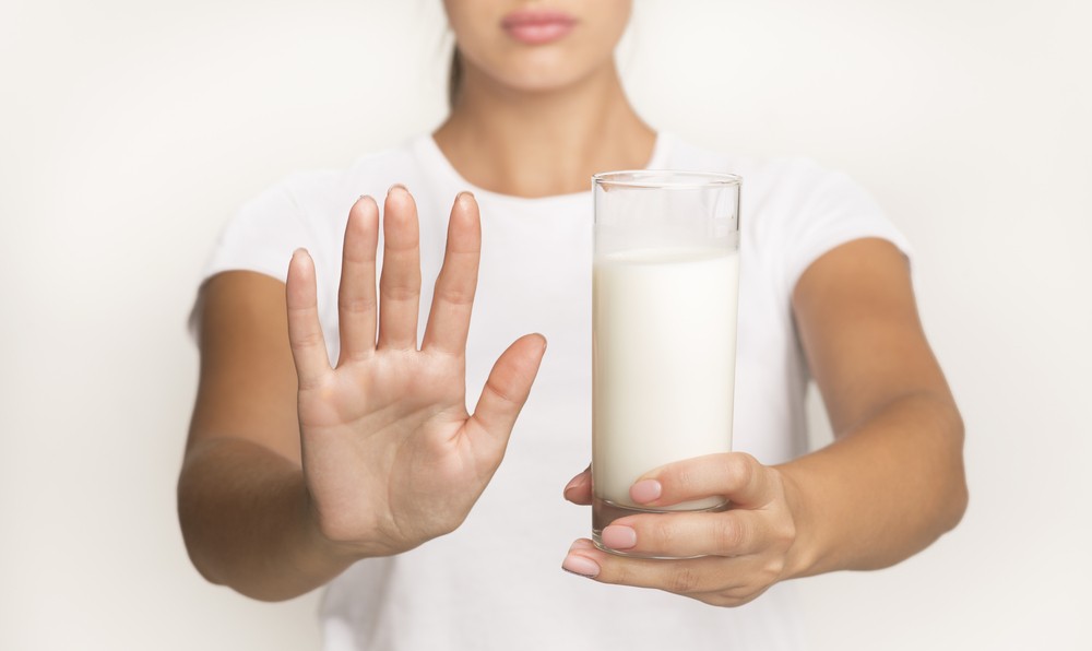 Alergia na mleko, kobieta trzyma szklankę mleka.
